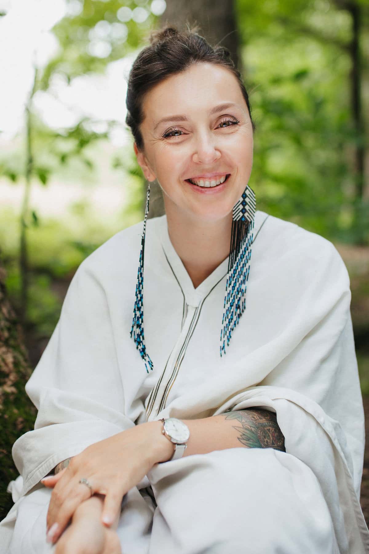 Mariya Garnet, Registered Psychotherapist (Qualifying), smiling outdoors in a white wrap top with green trees in the background